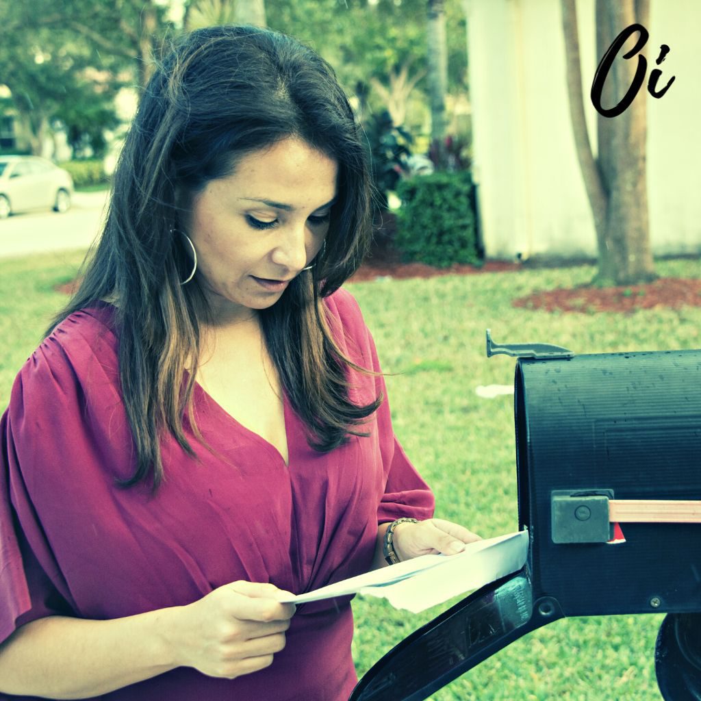 A woman is getting mail from the mailbox.